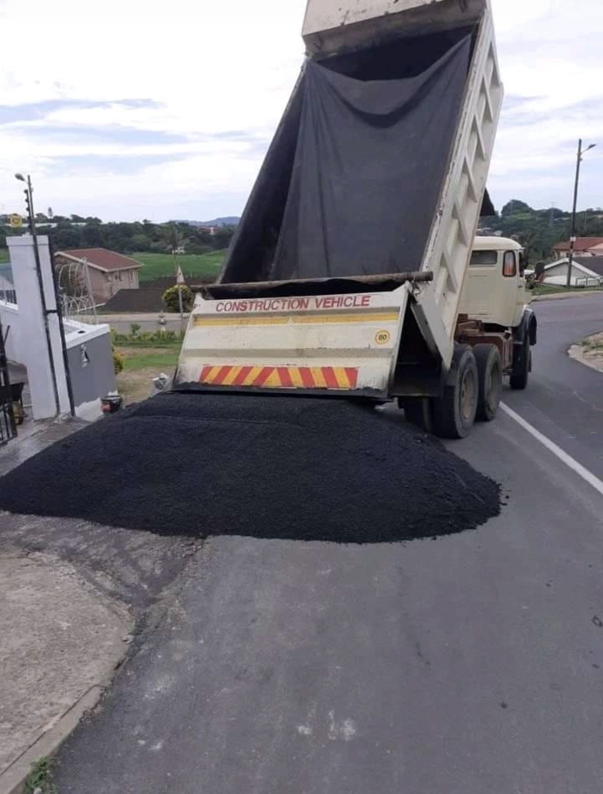 Construction vehicle unloading asphalt for a road paving project